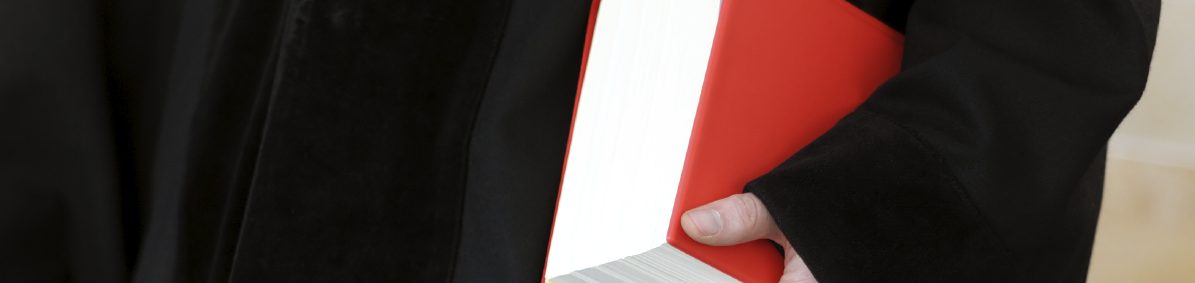 Richter hält einen Schönfelder, rotes Buch, in der Hand.